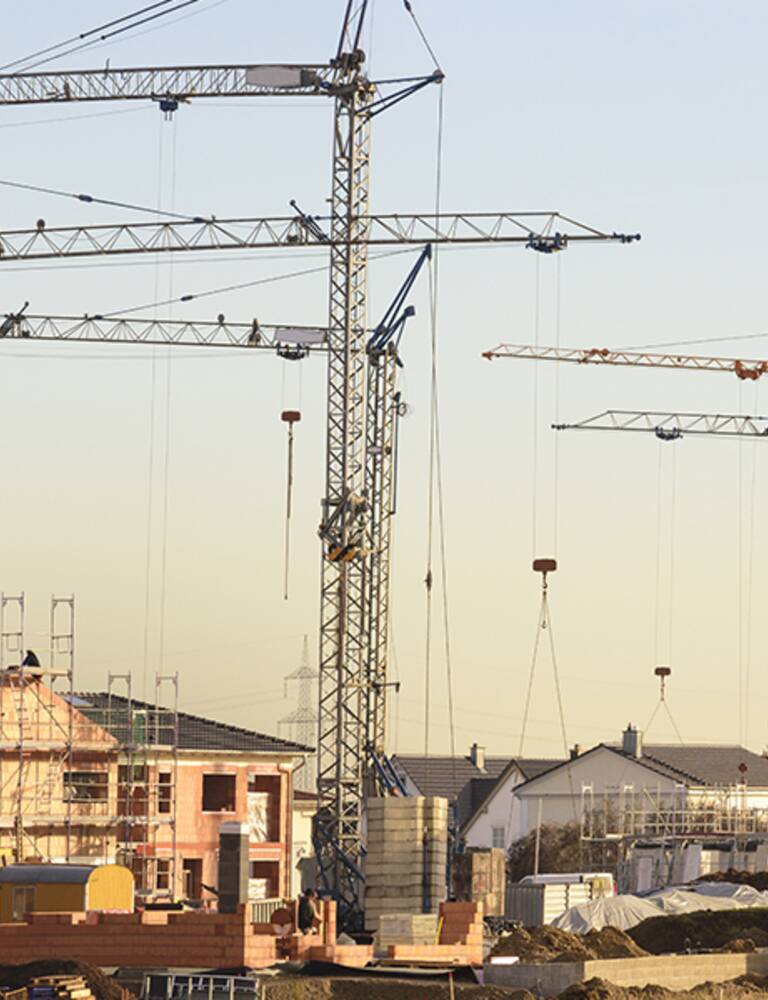 Kräne im Hintergrund und Neu- und Rohbauten im Vordergrund, im Abendlicht