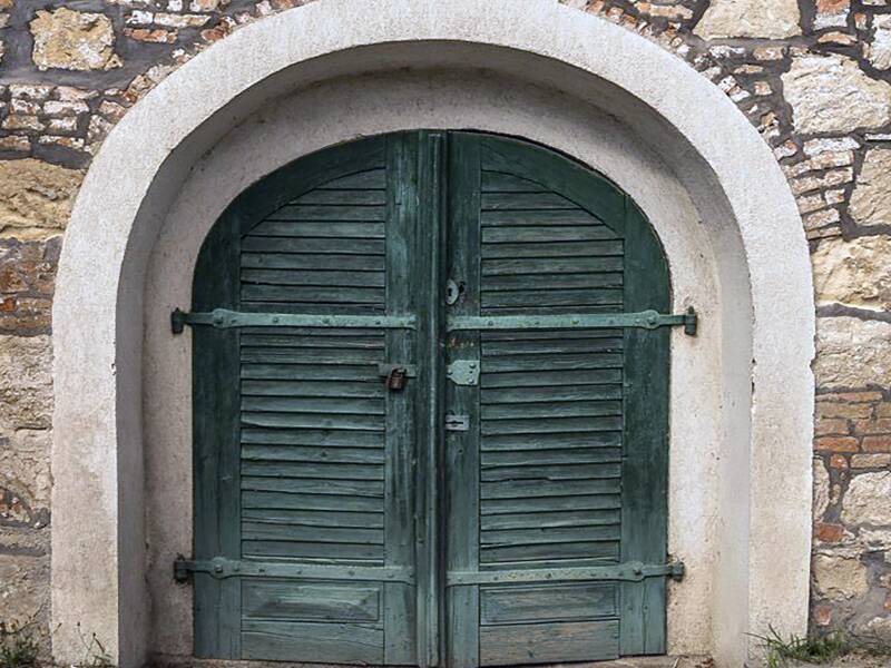 Detail Hausansicht Budajenö mit farbiger Tür und zwei runden Fenstern, rechts und links der Tür