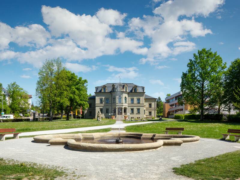 Neues Schloss (Rathaus) mit Springbrunnen im Vordergrund und Wolken am blauen Himmel im Hintergrund