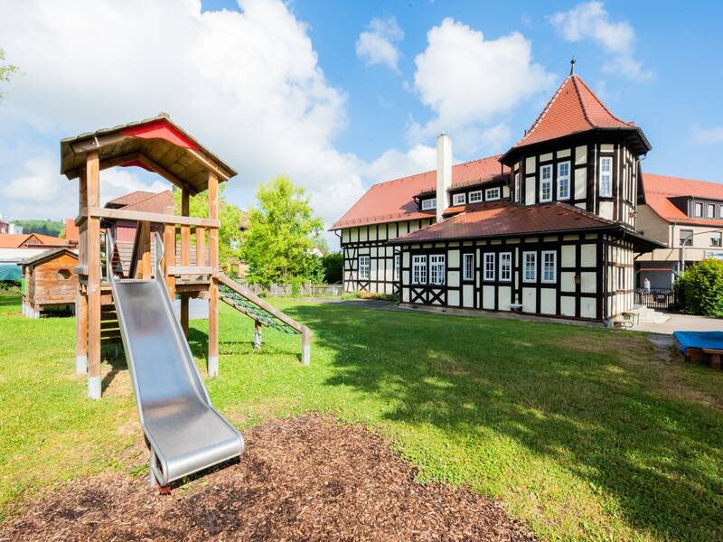 Kindergarten Gräfin Adele, links das denkmalgeschützte Fachwerkgebäude, rechts eine Rutsche