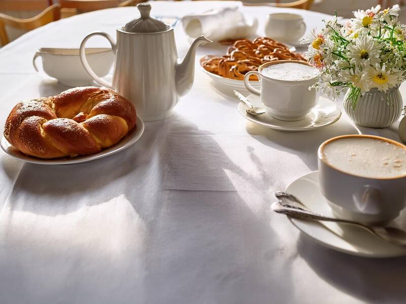 KI generiertes Bild, Kafeetafel mit weißer Tischdecke, hefezopf, Kaffee und Torte