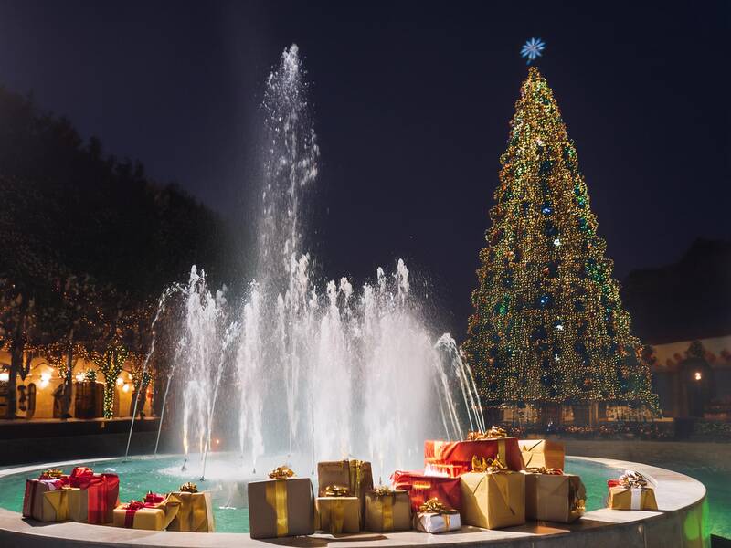 KI großer Brunnen mit Weihnachtsbaum im Hintergrund sowie Geschenke im Vordergrund