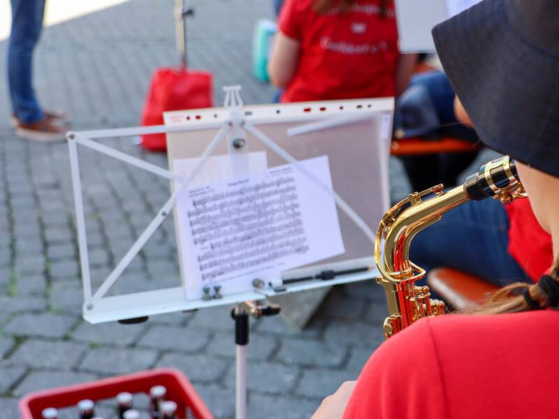 Stadtkapelle Gaildorf am Gaildorfer Samstag, Blick über die Schulter einer Muskantin auf Notenständer mit Noten in sommerlicher Atmosphäre auf dem Gaildorfer Marktplatz