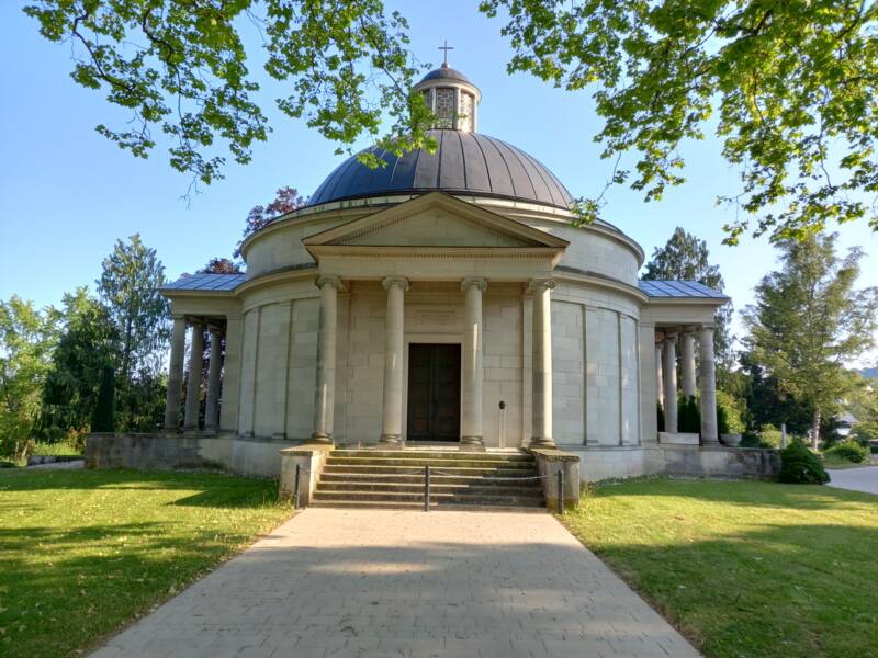 Frasch-Mausoleum im Stile der Grabkapelle auf dem Stuttgarter Rotenberg, im Vordergrund gepflasteter Weg, darüber Zweige und Äste eines Baumes